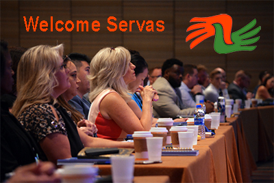 photo of people at conference table with Welcome Servas sign