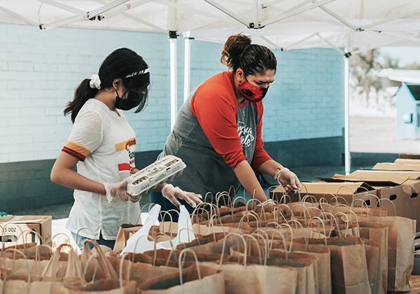 Photo of two women packing bags of food at a food pantry