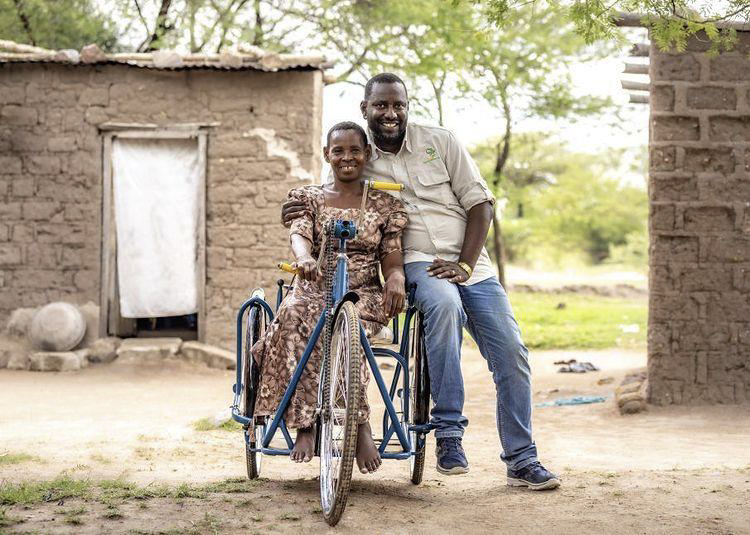 Photo of artist, David Kabambo, with disabled woman on a special tricycle
