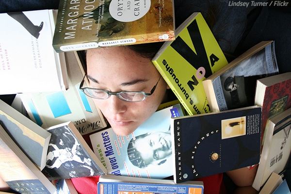 photo of young woman buried by books
